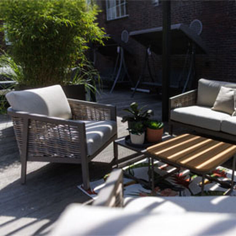 Gartensessel und Gartensofa in grau unter einer Pergola